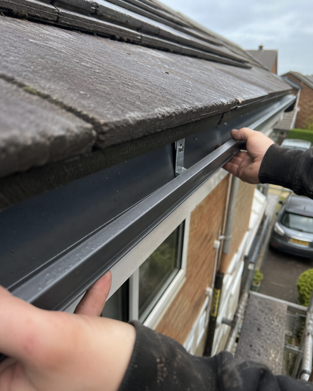 Close detail of anthracite seamless aluminium guttering being fitted