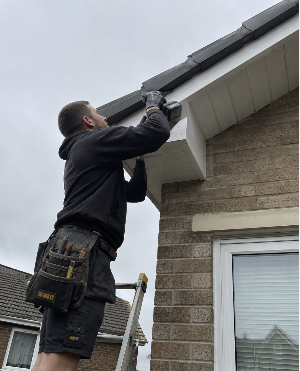 Roofer fixing new white UPVC fascia and soffit to a gable end